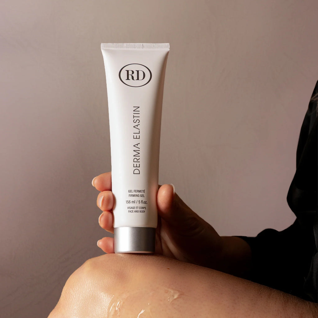 Une femme tient un Tube de crème derma elastin RD de gel fermeté 60ml et du gel sur sa jambe.